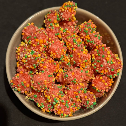 Pink freeze dried nerd gummy clusters with rainbow sprinkles in a dark grey bowl